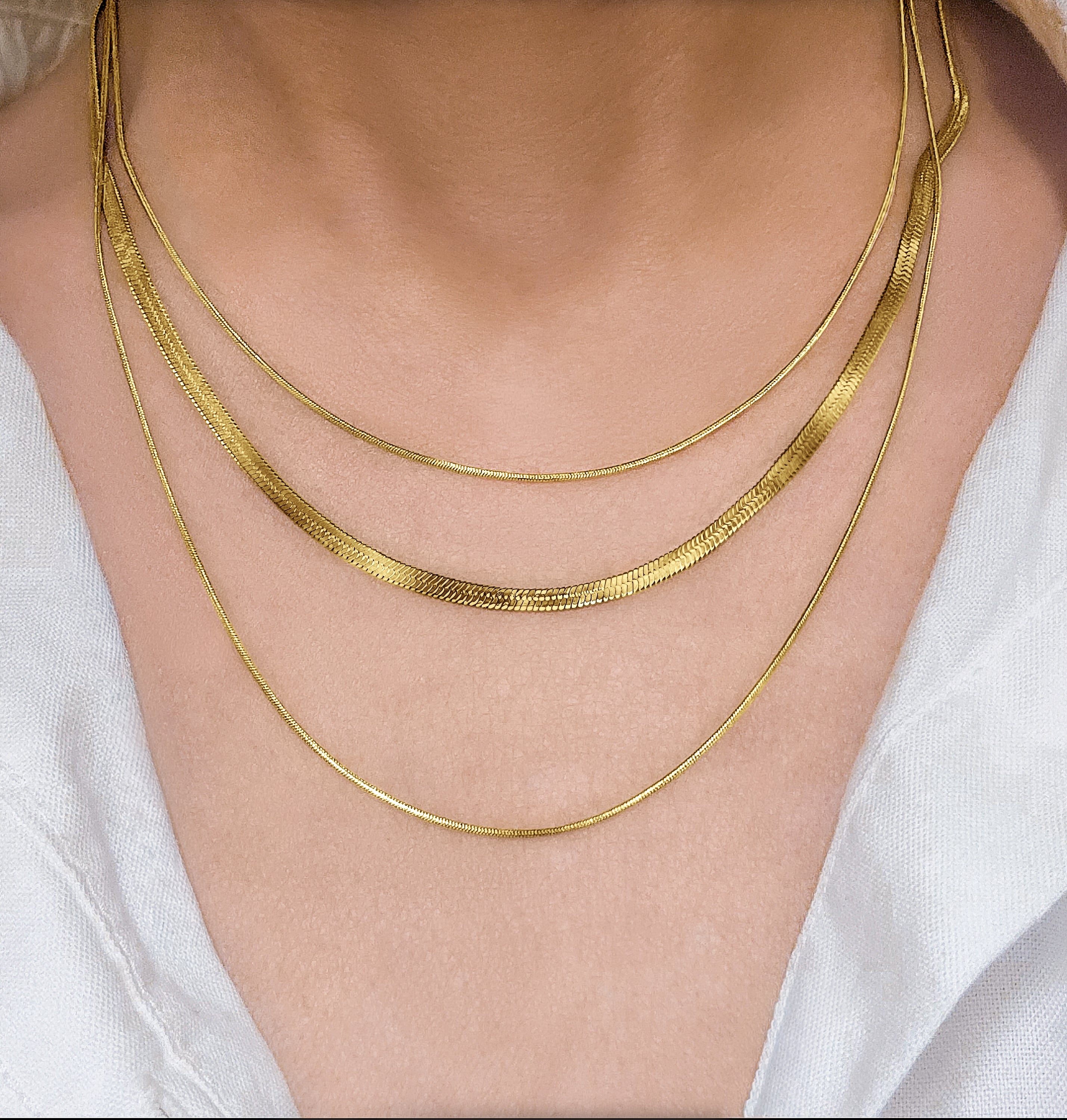 RALLUNA triple chain gold necklace worn over a white top