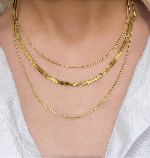 RALLUNA triple chain gold necklace worn over a white top