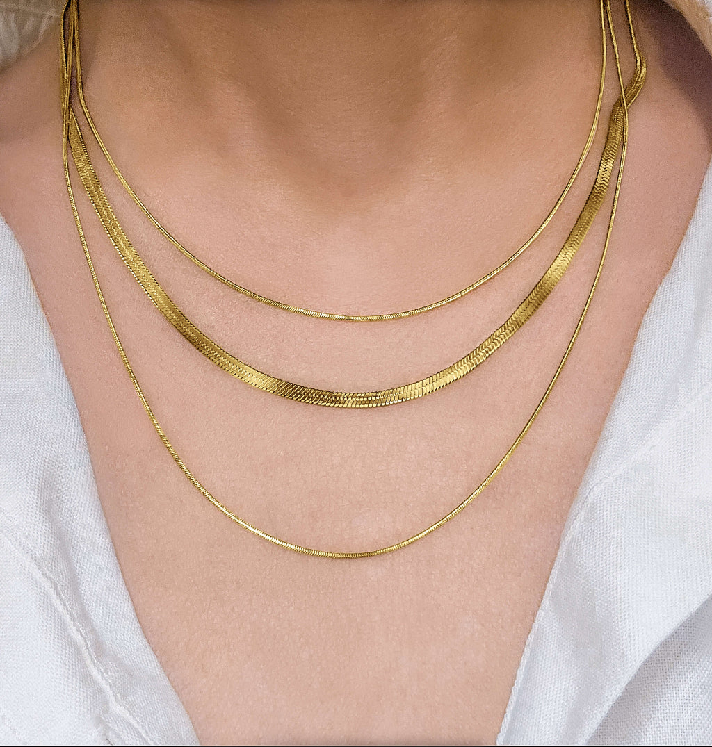RALLUNA Triple Layer Herringbone Necklace in gold-tone 316 stainless steel on model wearing a white top