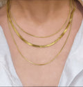 RALLUNA Triple Layer Herringbone Necklace in gold-tone 316 stainless steel on model wearing a white top